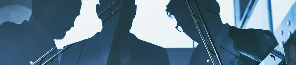 Drei Leute sind an einer Glaswand gespiegelt